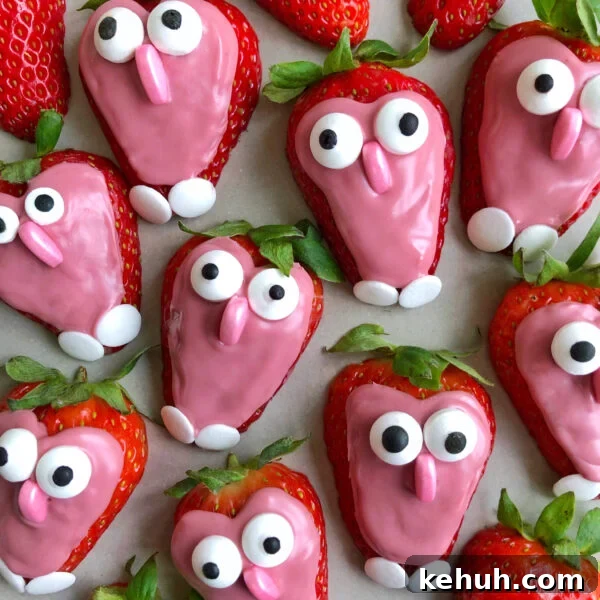 Strawberries coated with pink chocolate, decorated with googly candy eyes and small white candy feet to resemble owls.