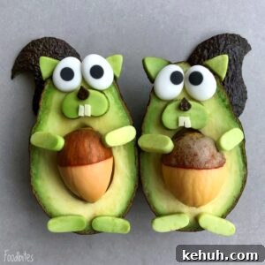 Two avocado halves are decorated with avocado pieces to resemble squirrels, using the pits to resemble nuts with added shapes for eyes, ears, tails, arms, and teeth.