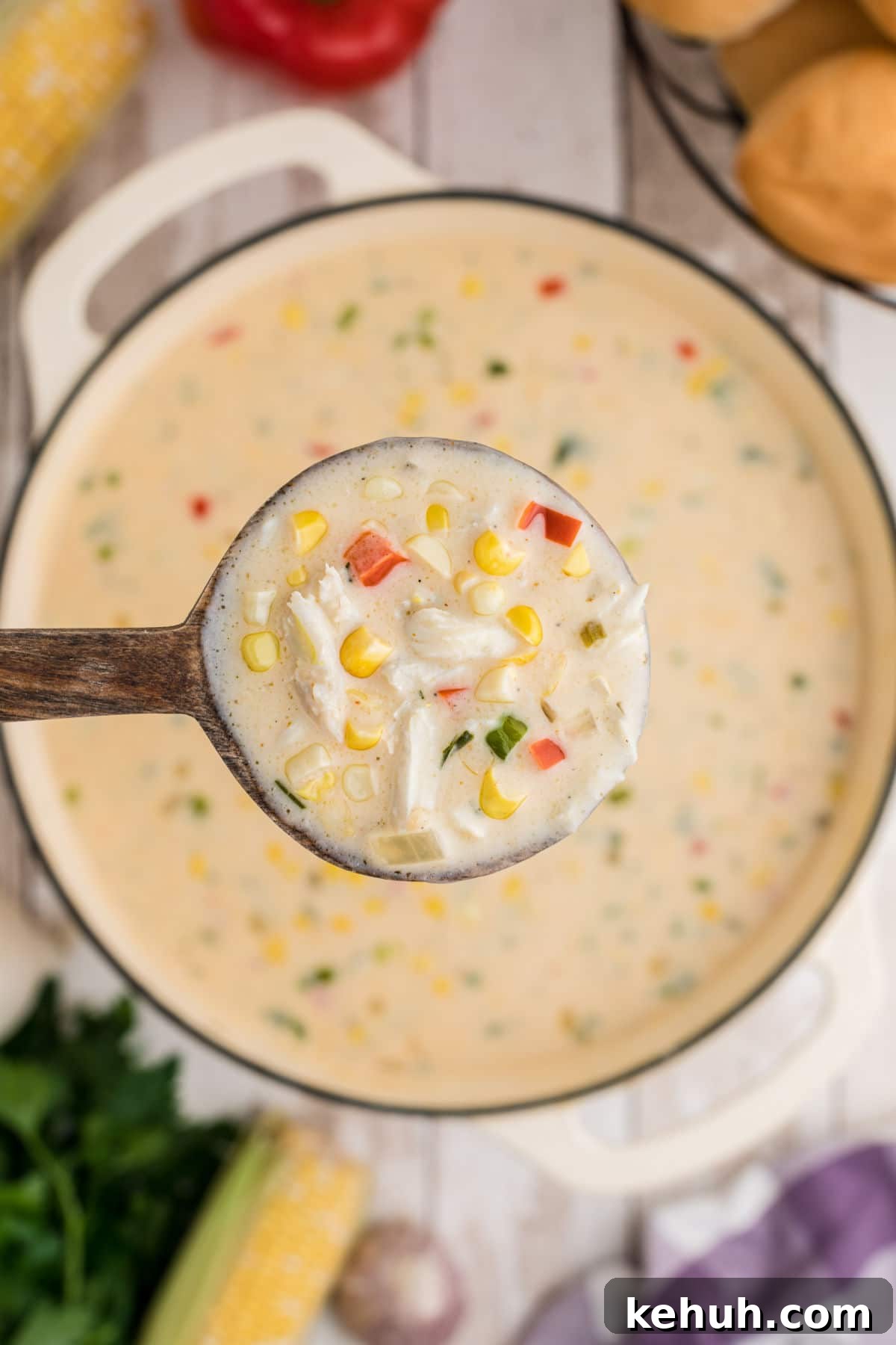 close up of a spoon full of corn and crab bisque above the pot