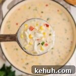 A large pot of corn and crab bisque with a spoon lifting some out to show you.