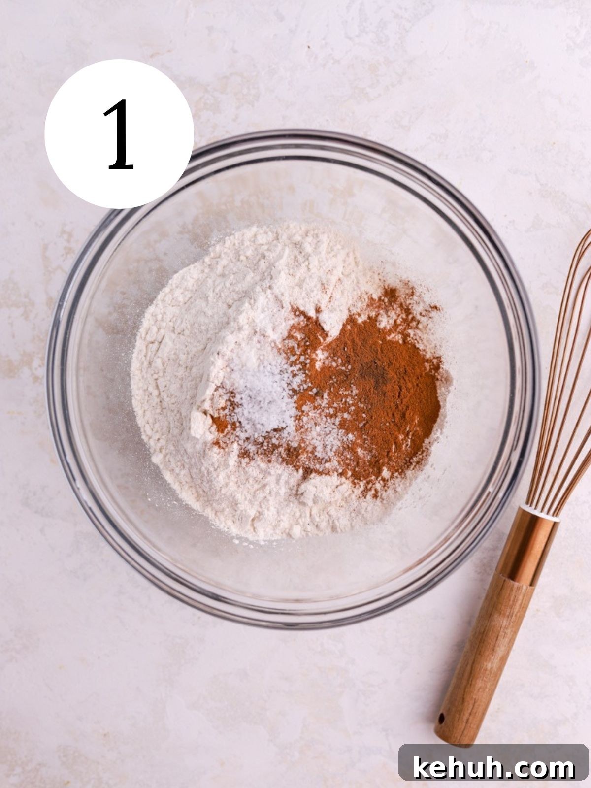 Moist Pumpkin and Carrot Layer Cake Recipe 4 A mixing bowl with flour, spices, and salt and a whisk next to it.
