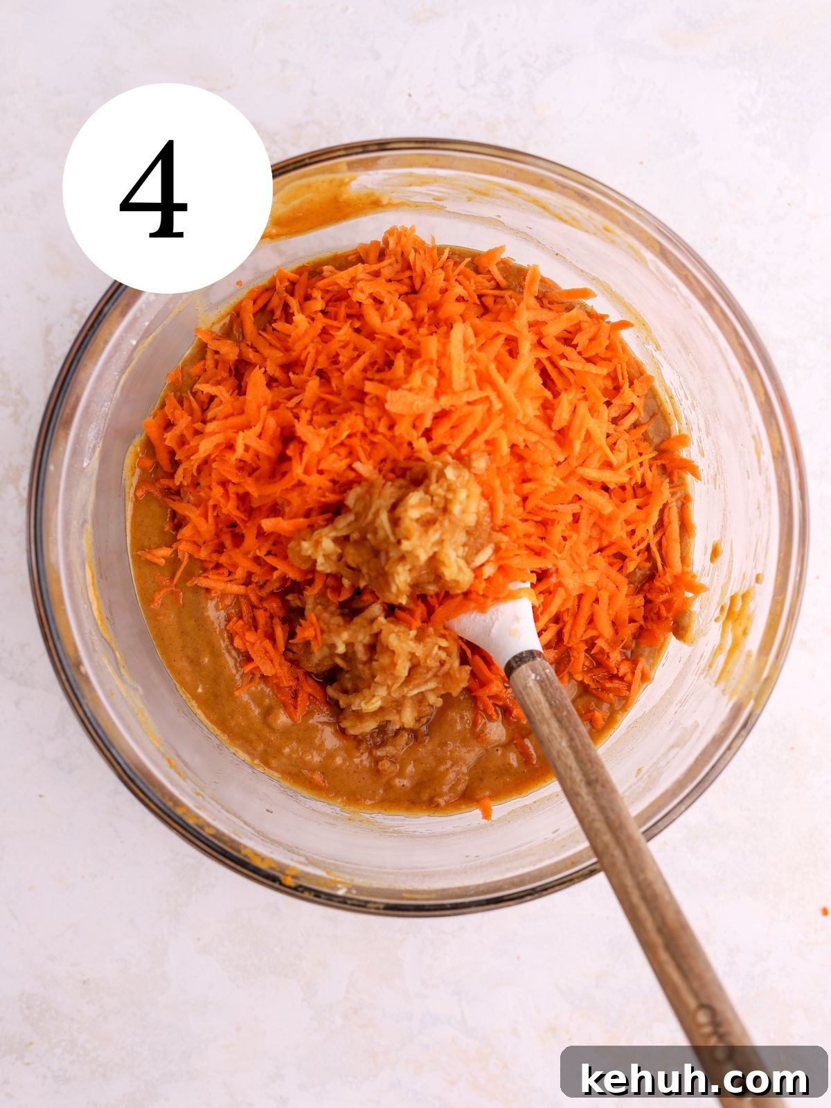 Moist Pumpkin and Carrot Layer Cake Recipe 7 A mixing bowl with shredded carrots being stirred into pumpkin cake batter with a spatula.