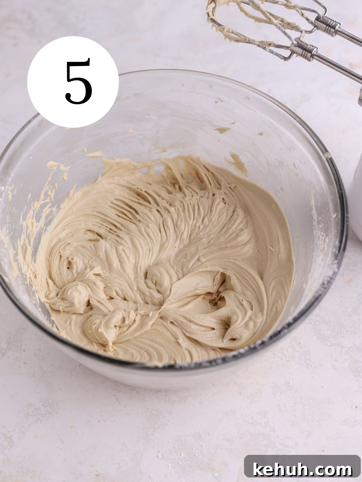 Moist Pumpkin and Carrot Layer Cake Recipe 8 A glass mixing bowl with brown sugar cream cheese frosting mixed together.