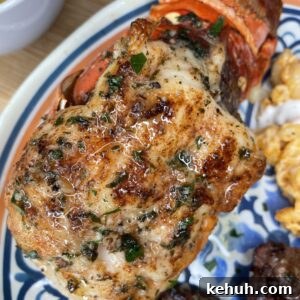 Close-up of a grilled lobster tail seasoned with herbs and spices on a decorative plate, with side dishes including scrambled eggs and pieces of grilled meat visible nearby.