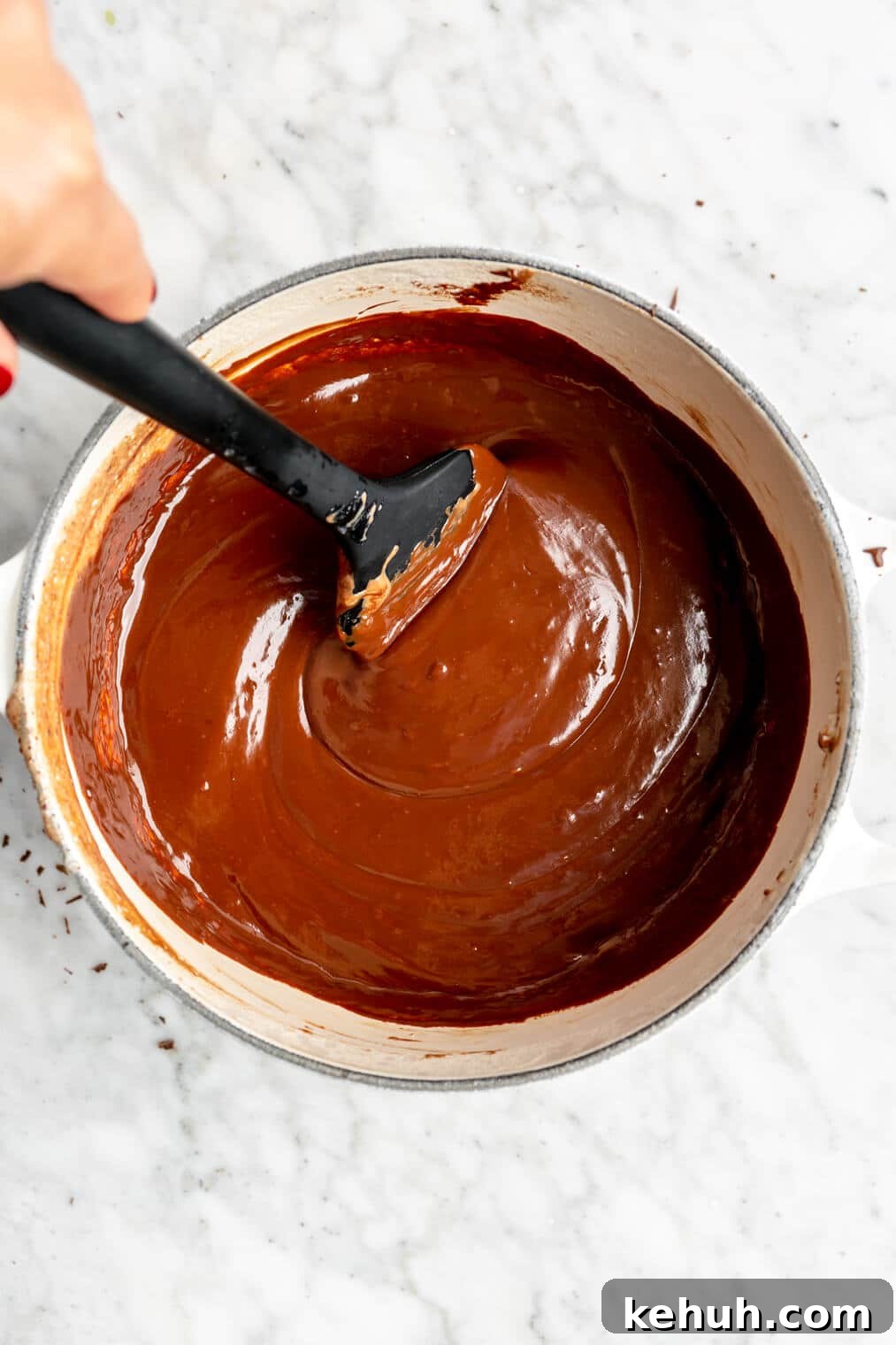 220824_Bourbon Pecan Truffles-11 Black spatula in chocolate ganache in a white saucepan.