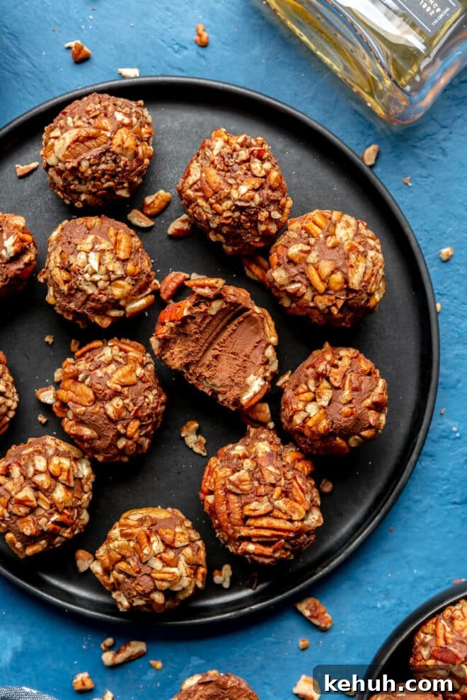 Authentic Kentucky Bourbon Balls Recipe: No-Bake Holiday Treat 4 Black plate of bourbon balls on a blue surface with one bourbon ball with bite taken out of it in the middle.