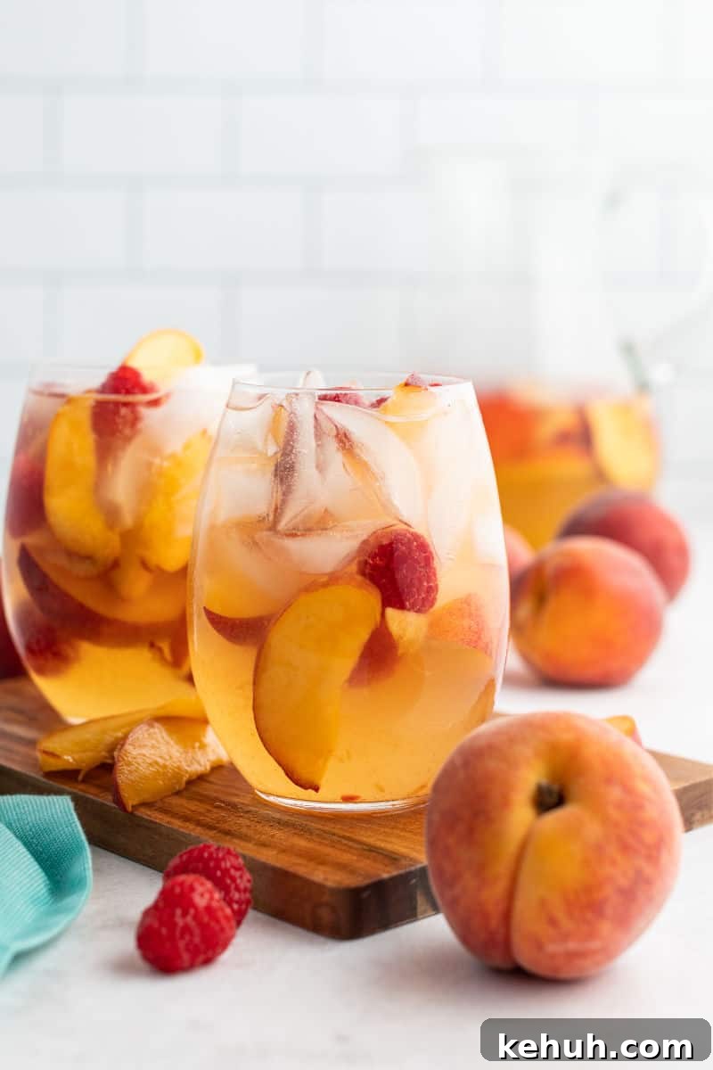 Bring on a never-ending pitcher of this Raspberry Peach Moscato Punch! Some wine, Sprite, and lots of fruit is a crazy good combo made for sharing! glass of raspberry peach moscato punch next to a peach