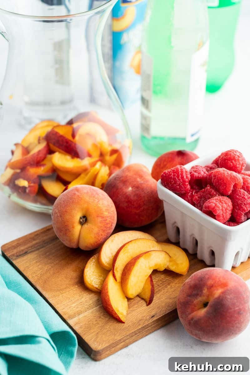 Bring on a never-ending pitcher of this Raspberry Peach Moscato Punch! Some wine, Sprite, and lots of fruit is a crazy good combo made for sharing! sliced peaches on a cutting board next to whole peaches and a basket of raspberries