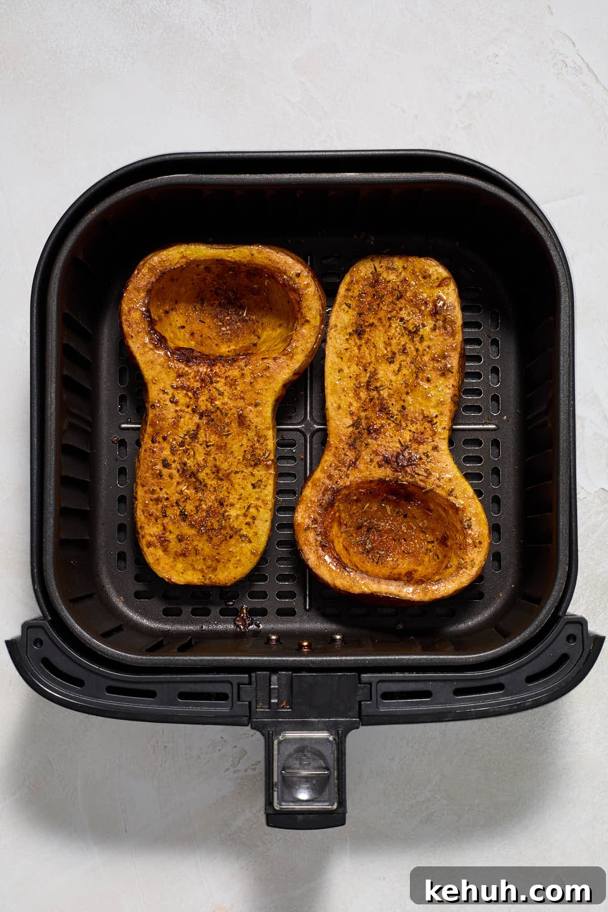 Finished squash halves in an air fryer basket.