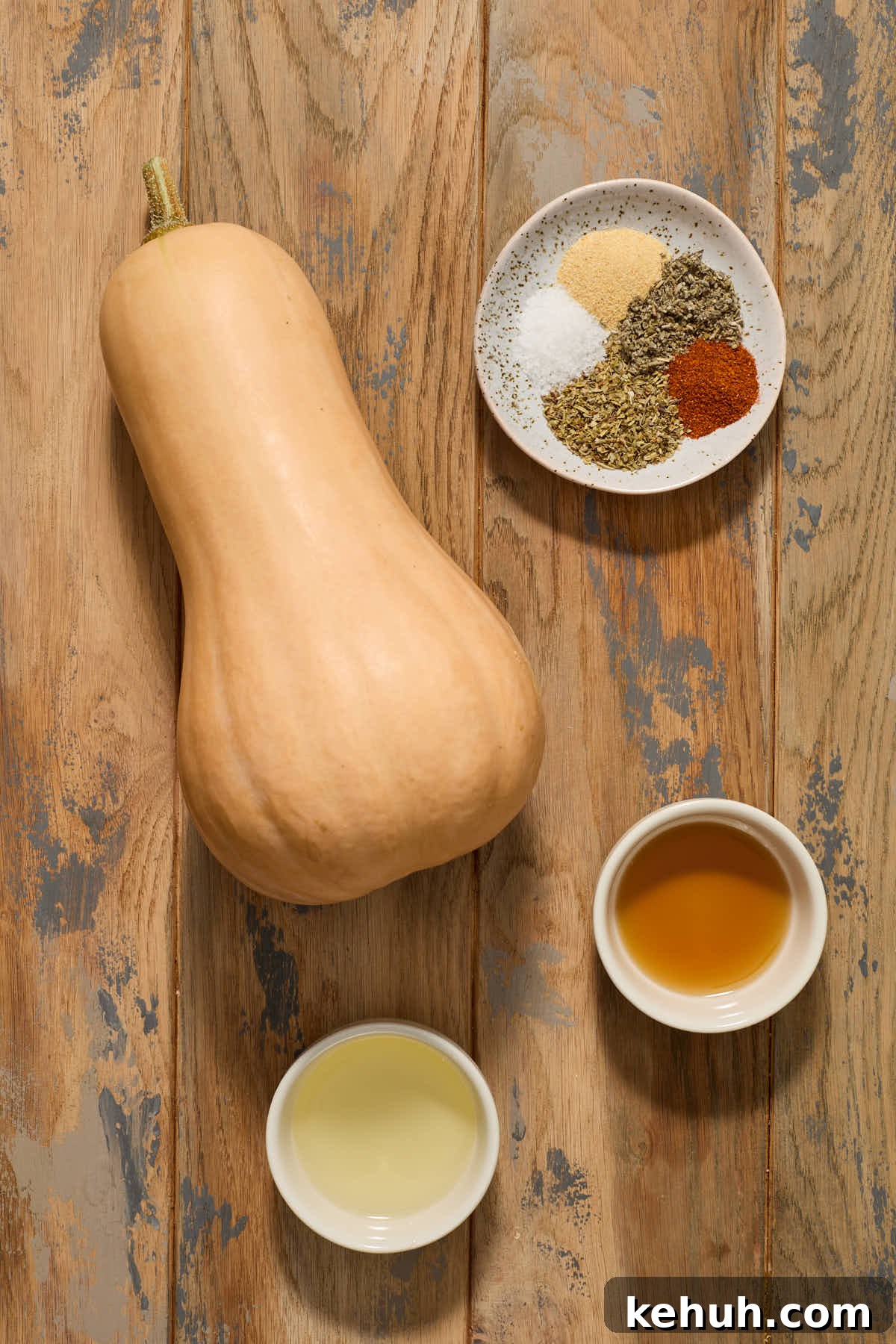 Ingredients to make air fryer butternut squash arranged individually on a wooden surface.