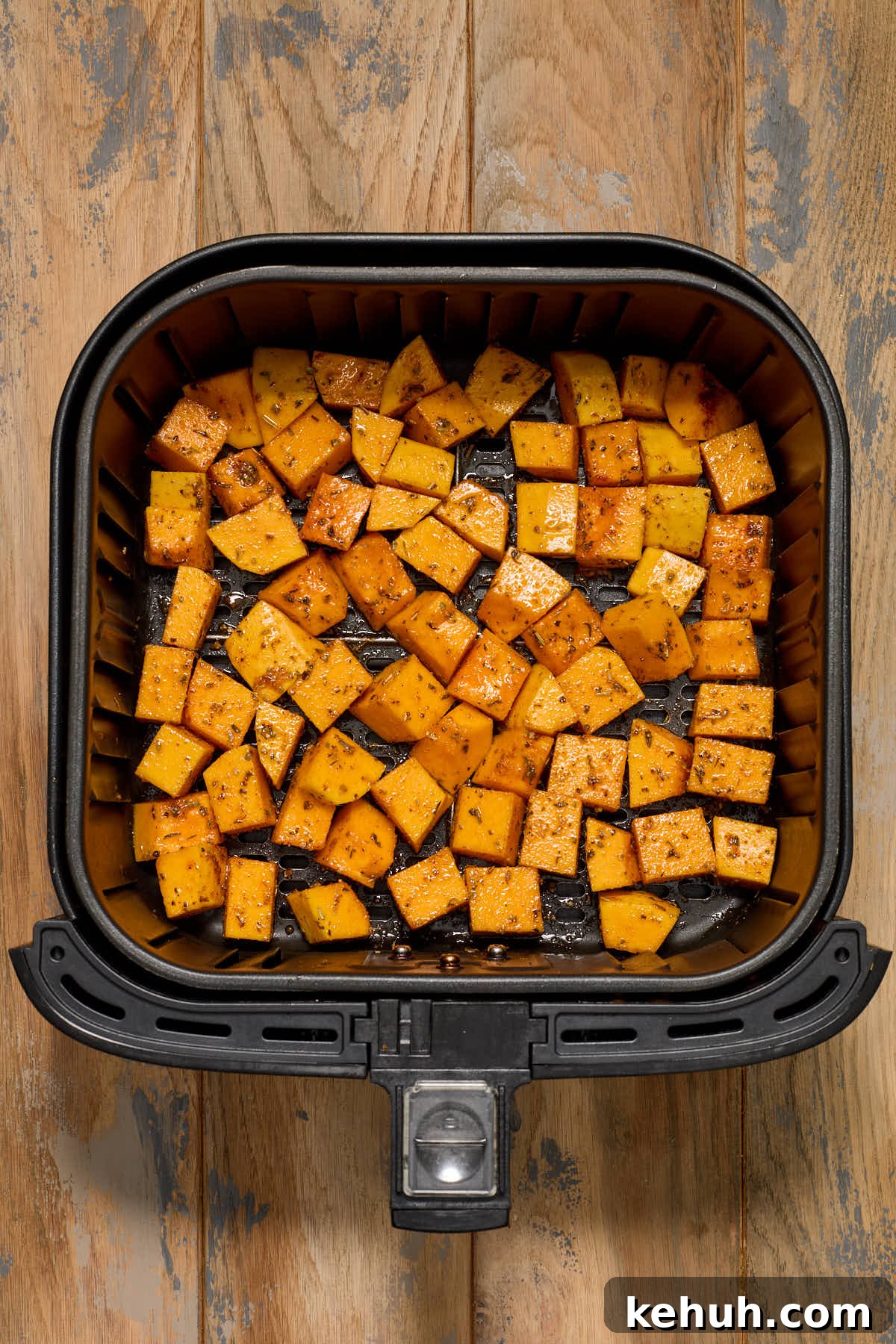 Seasoned squash cubes in an air fryer basket.