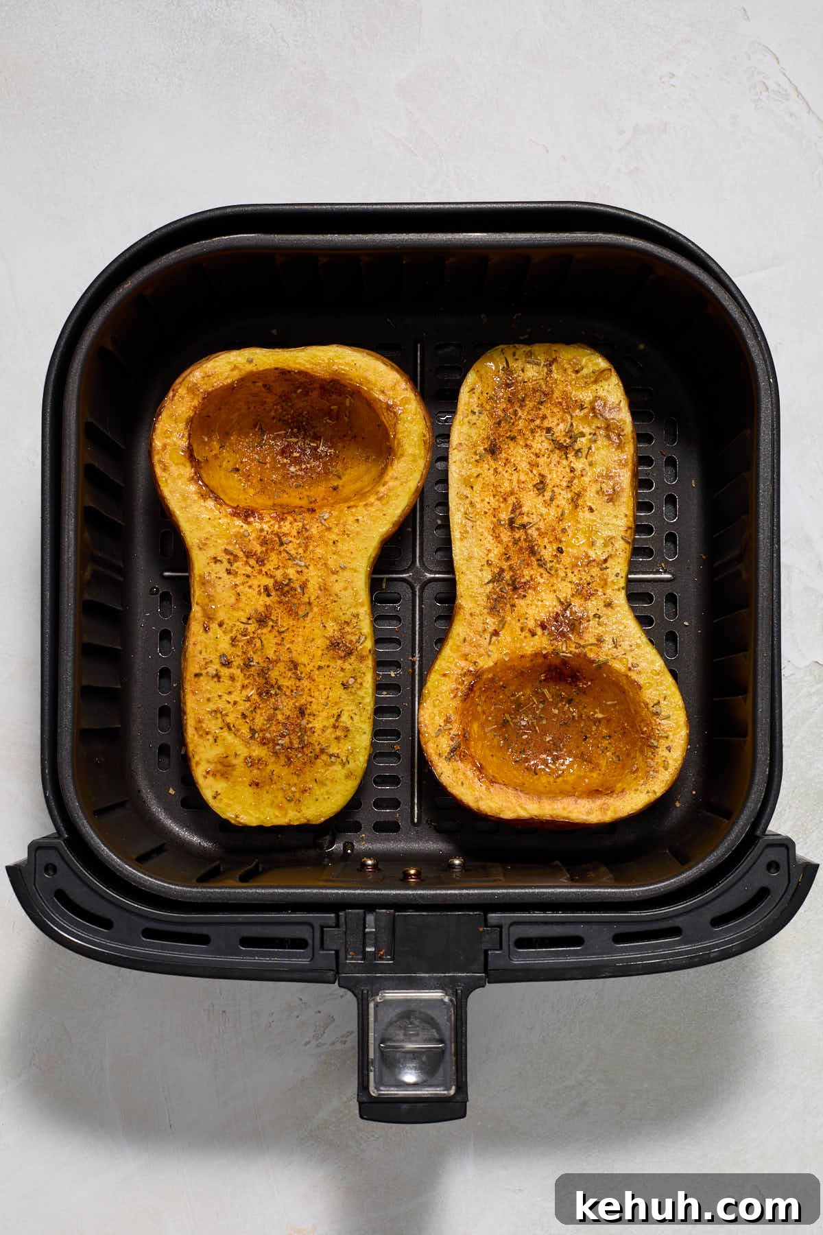 Squash halves with maple syrup and seasonings sprinkled on.