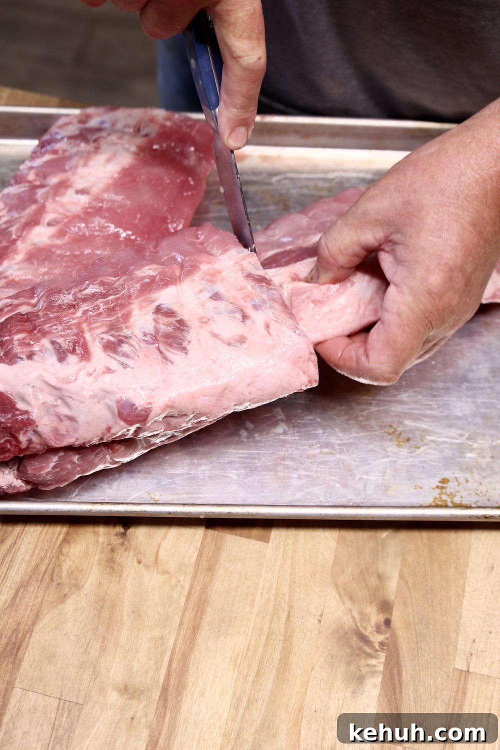 cutting racks of ribs in half on a sheet pan