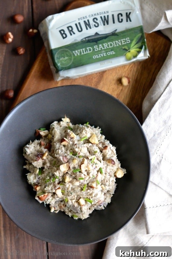 overhead shot of a black bowl filled with Hazelnut Sardines Rillettes with a can of sardines in the background 