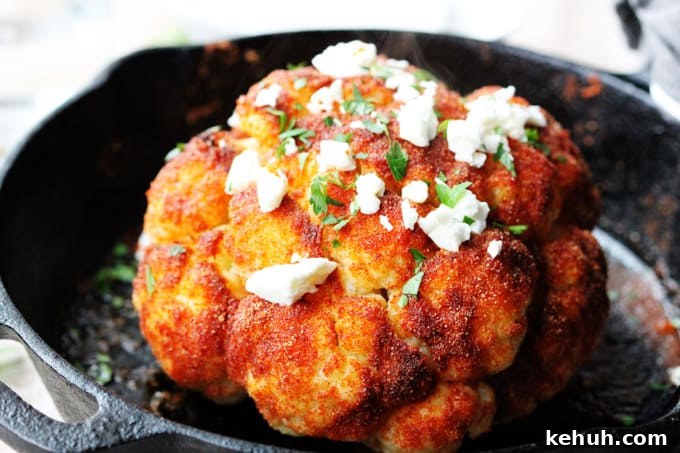 Whole roasted cauliflower head in a skillet