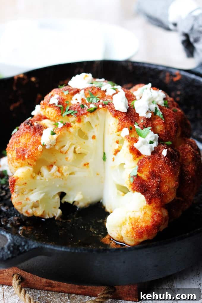 Cut up roasted head of cauliflower with feta and spices.