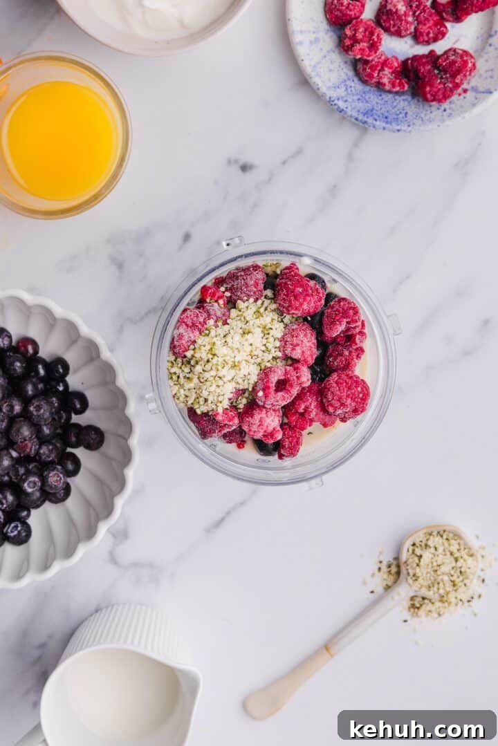 Overhead photo of ingredients for blueberry raspberry smoothie in a blender cup, unblended