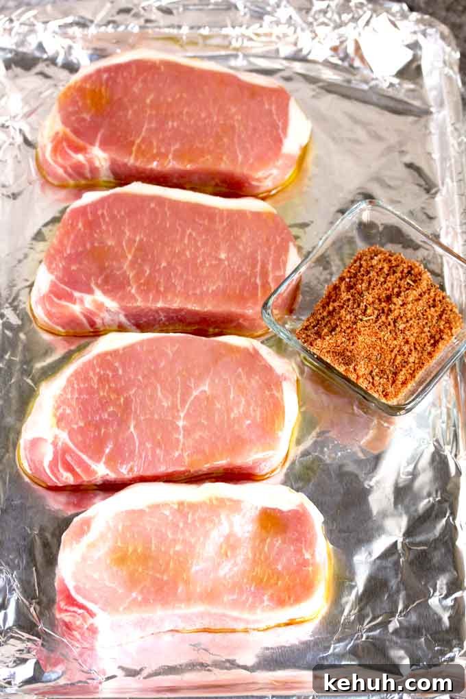 Raw pork chops on a sheet pan and a bowl of dry rub mix.