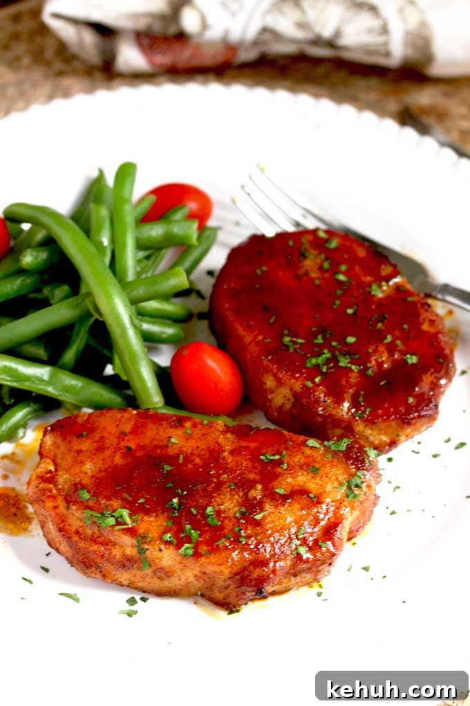 Two Baked Pork Chops on a white plate.
