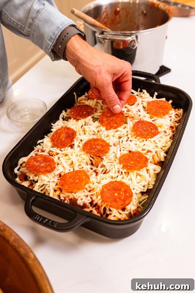 Cheesy Pizza Casserole Recipe with Sausage and Peppers 12 Layering pepperoni overtop mozzarella on a pasta bake.
