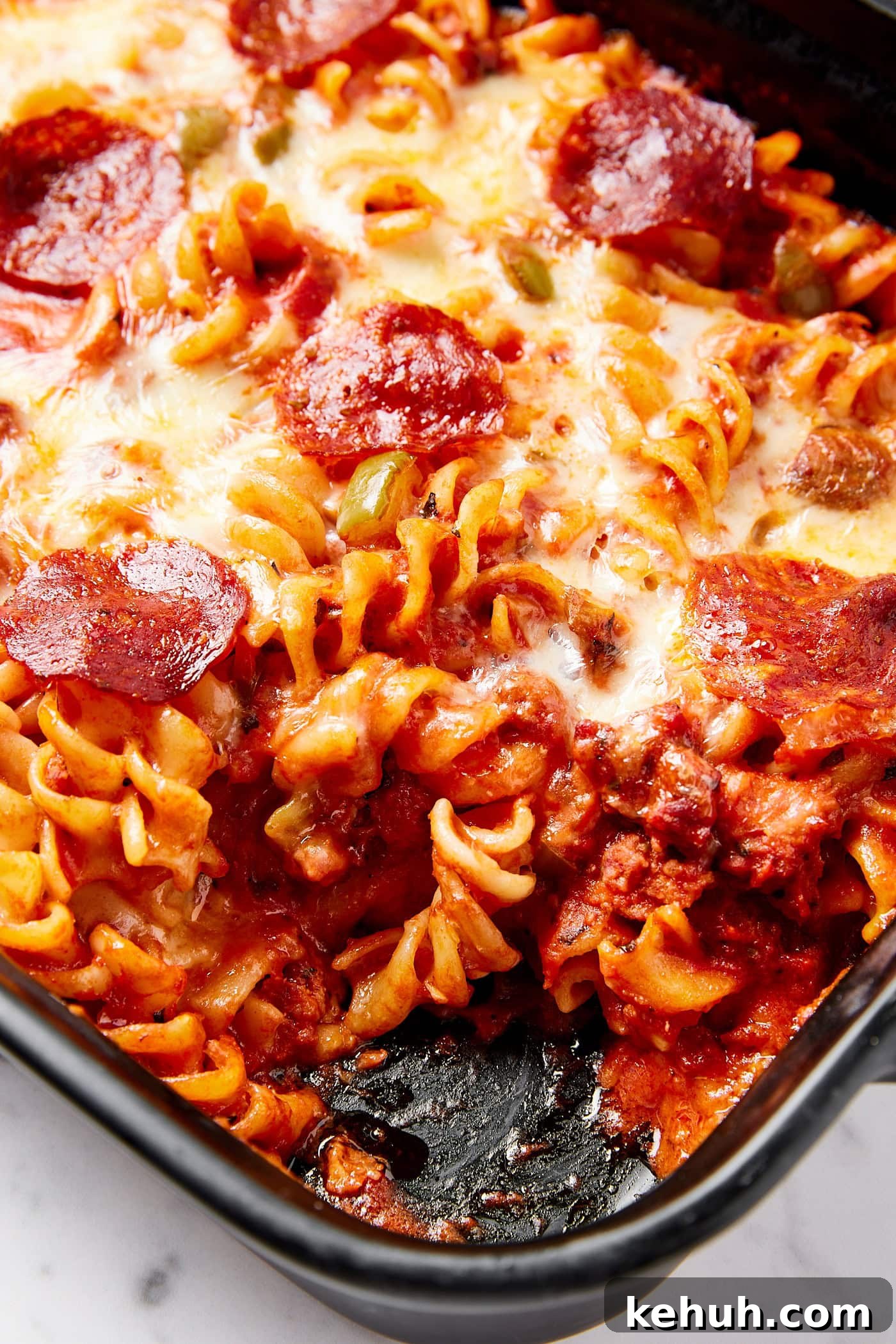 Cheesy Pizza Casserole Recipe with Sausage and Peppers 15 Pasta inside a casserole dish with tomato sauce, cheese, and pepperonis.