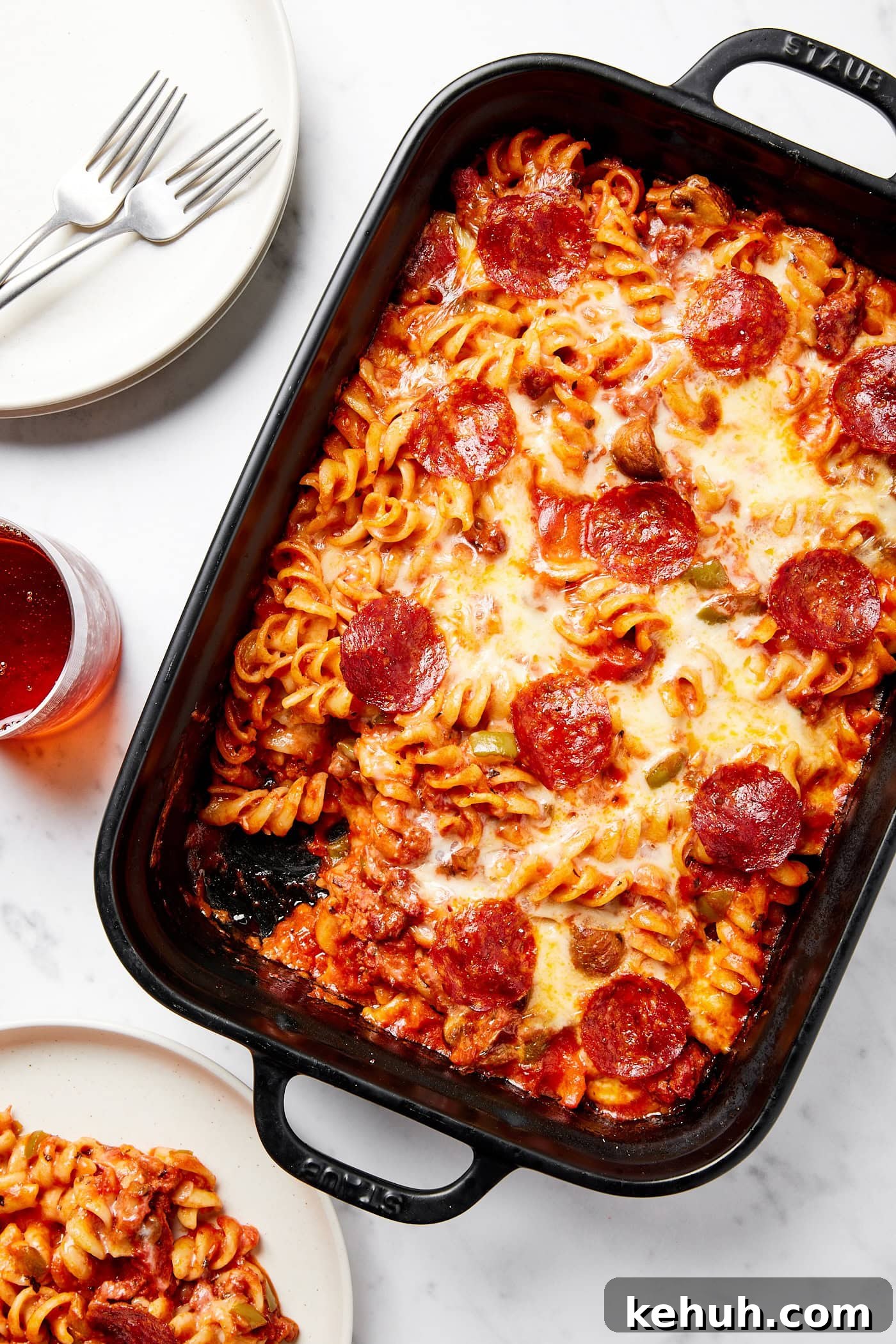 Cheesy Pizza Casserole Recipe with Sausage and Peppers 16 Black baking dish filled with casserole with cheese and pepperonis on top with a serving taken out.