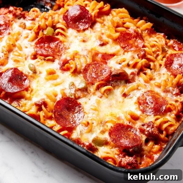 Cheesy Pizza Casserole Recipe with Sausage and Peppers 17 Baked pizza casserole with cheese and pepperonis on top in black baking dish.
