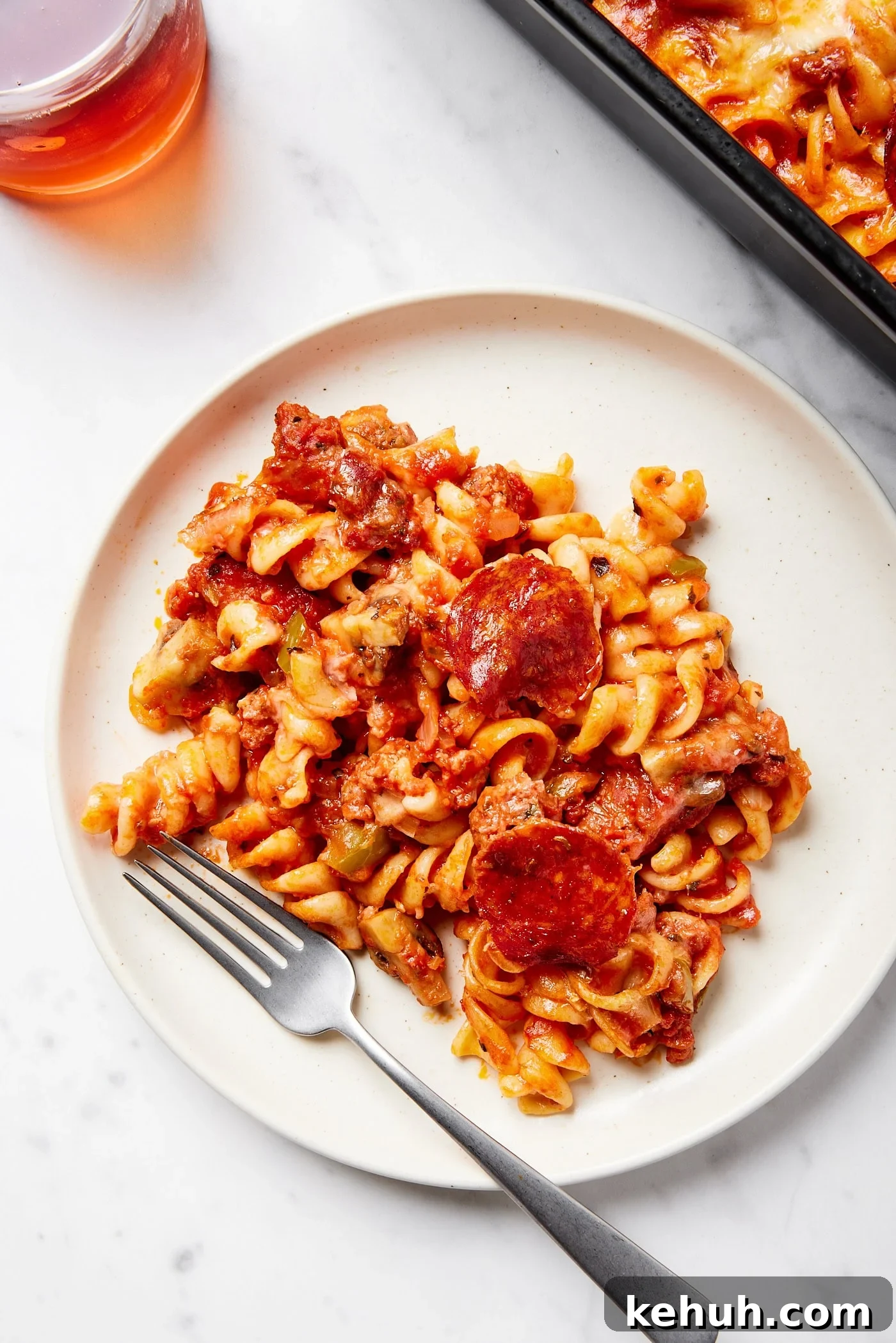 Cheesy Pizza Casserole Recipe with Sausage and Peppers 3 White plate with a serving of pizza casserole with fork on plate.