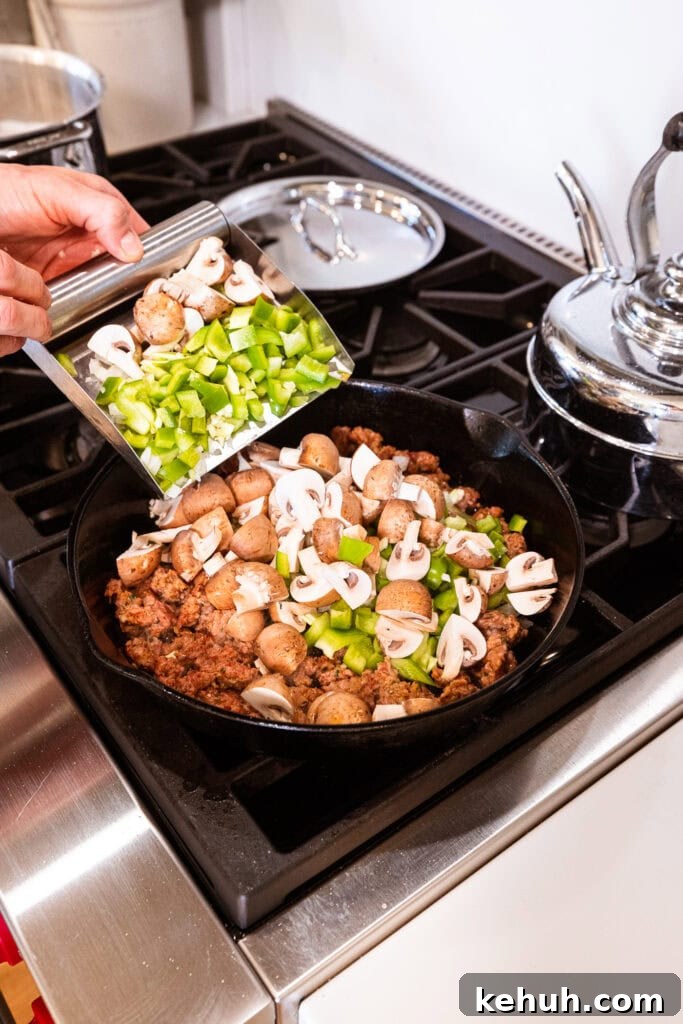 Cheesy Pizza Casserole Recipe with Sausage and Peppers 8 Vegetables get added to sausage browning on the stove.