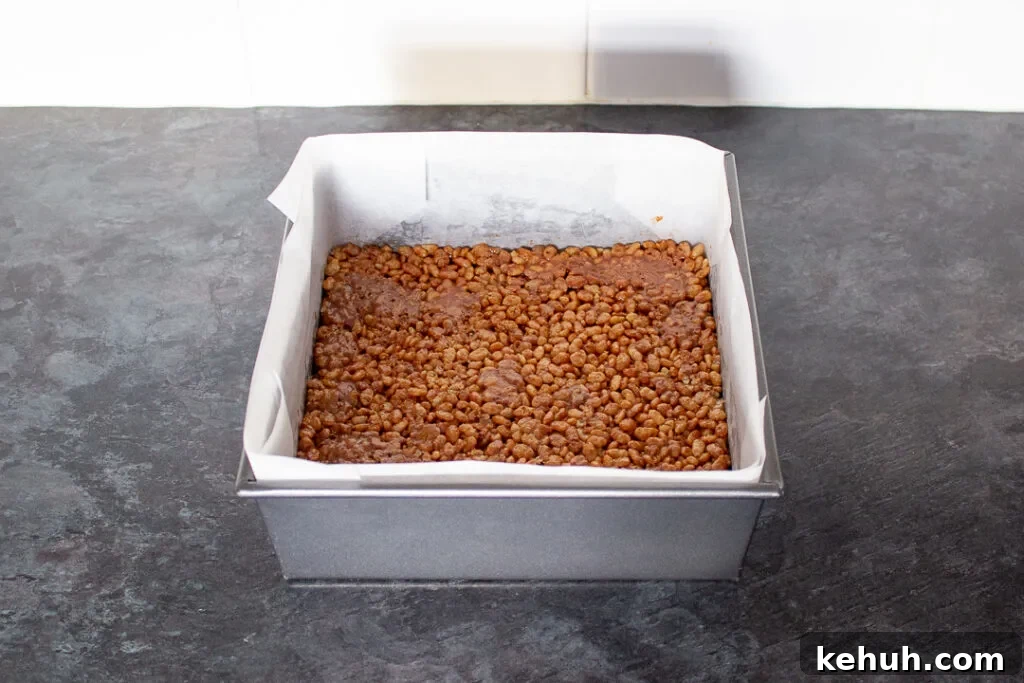 Mars Bar and Rice Krispie mixture pressed into a lined square baking tin.