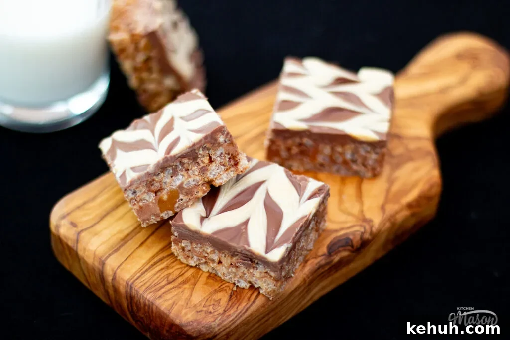 Mars Bar Slice bars on a wooden board, with a glass of milk to the side.