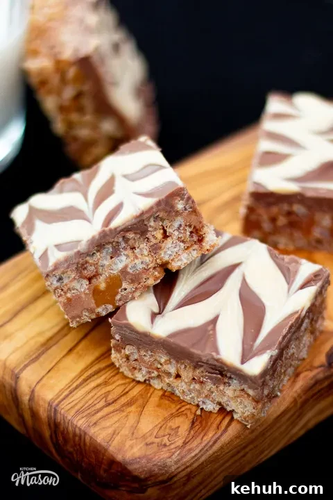 Several slices of Mars Bar slice on a wooden chopping board.