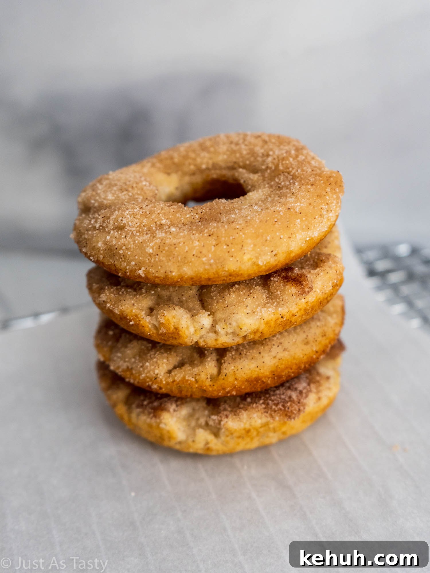 Gluten-Free Eggless Cinnamon Donuts Recipe 2 Stack of cinnamon donuts on white parchment paper.