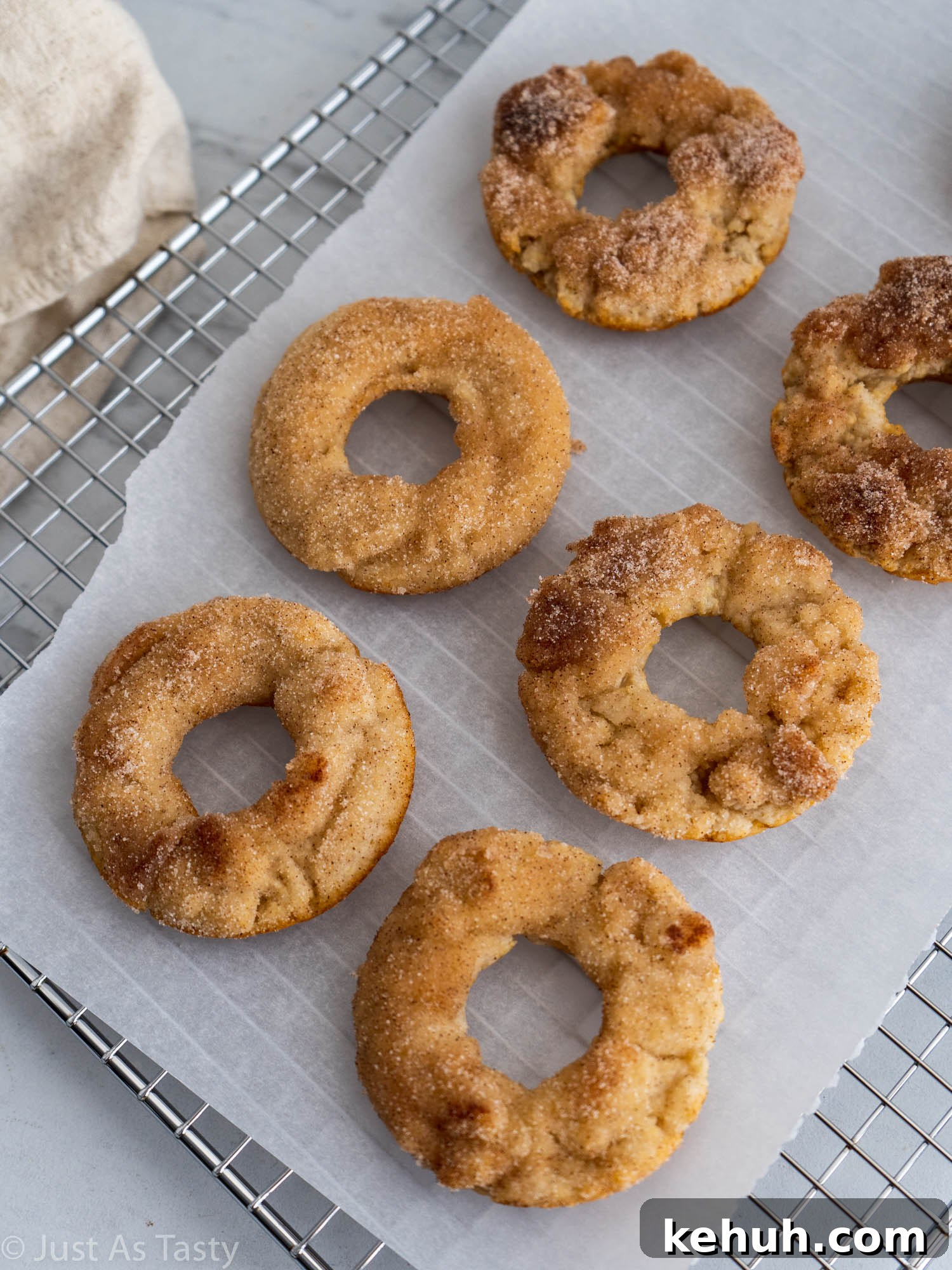 Gluten-Free Eggless Cinnamon Donuts Recipe 4 Donuts topped with cinnamon sugar on white parchment paper.