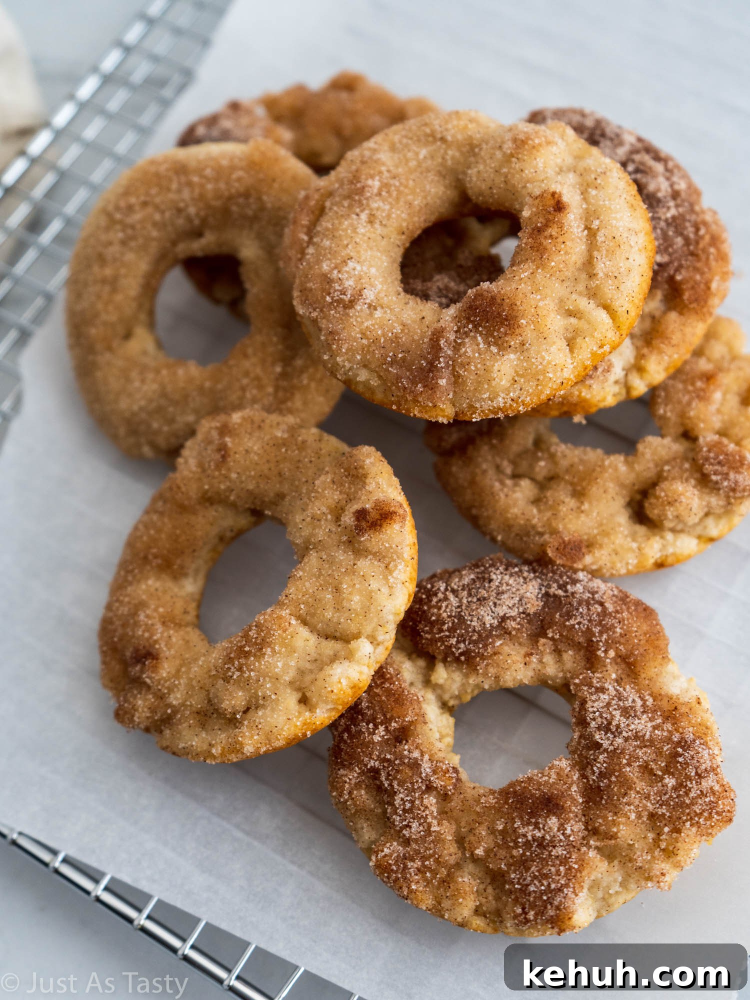Gluten-Free Eggless Cinnamon Donuts Recipe 5 Baked donuts piled onto white parchment paper.