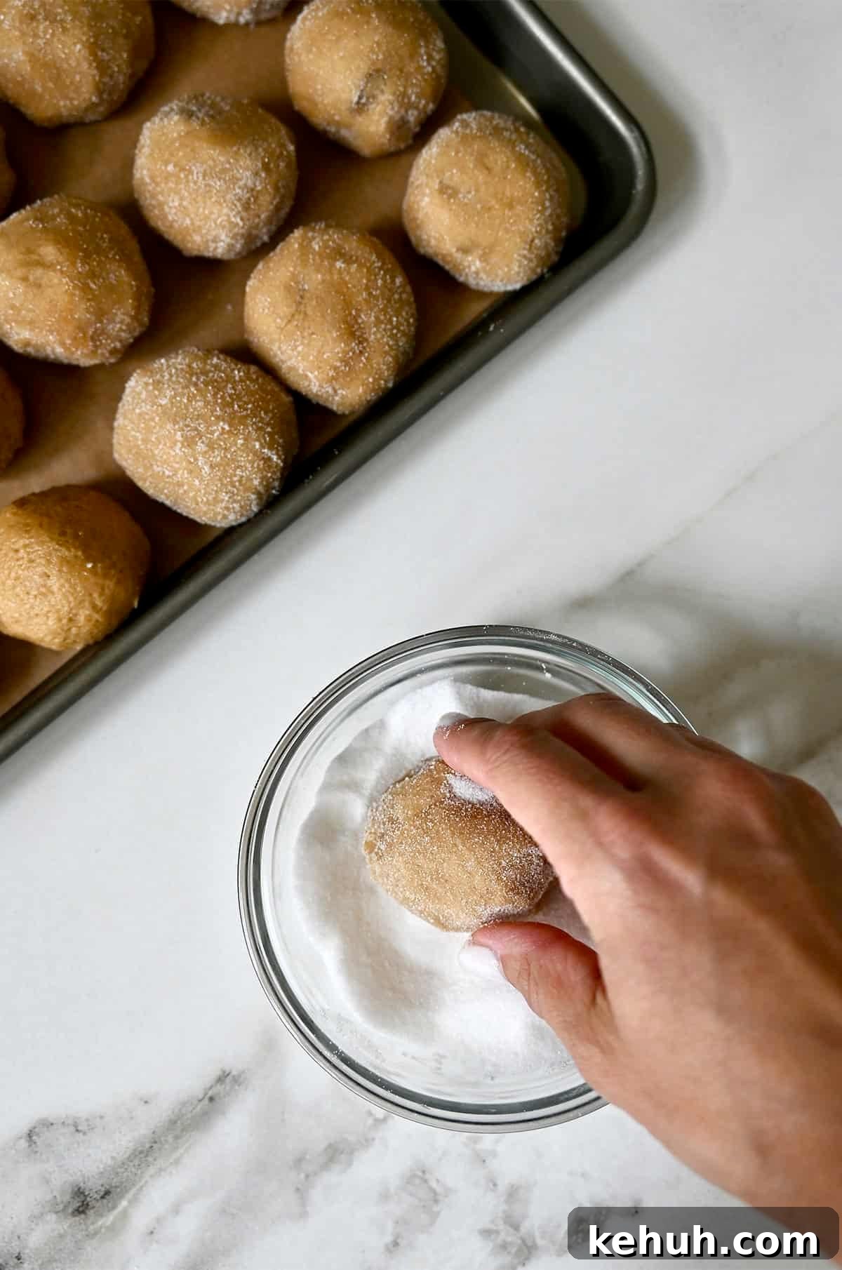 Rolling peanut butter dough balls in granulated sugar.