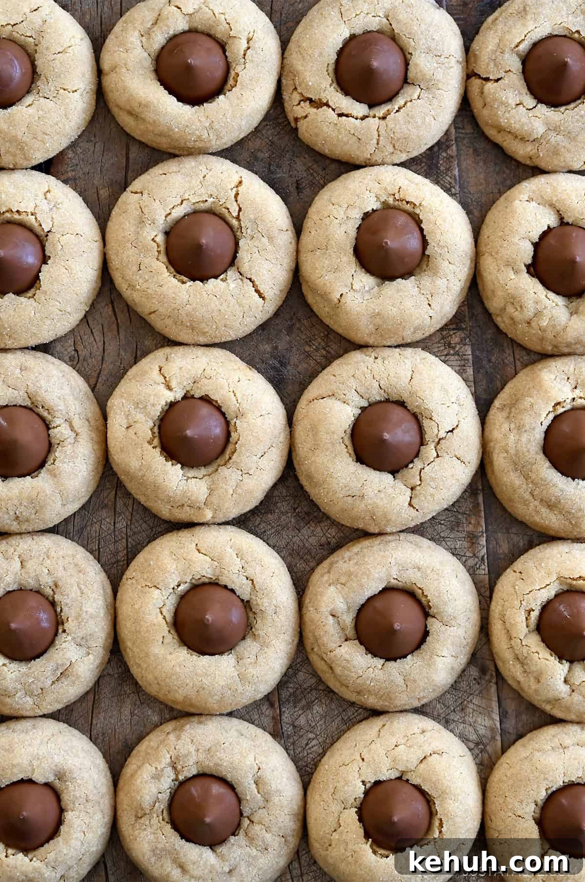 Four perfect rows of peanut butter blossoms on a wooden table.