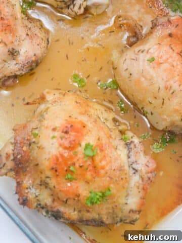 Honey and lemon baked chicken thighs with parsley on top in a baking dish.