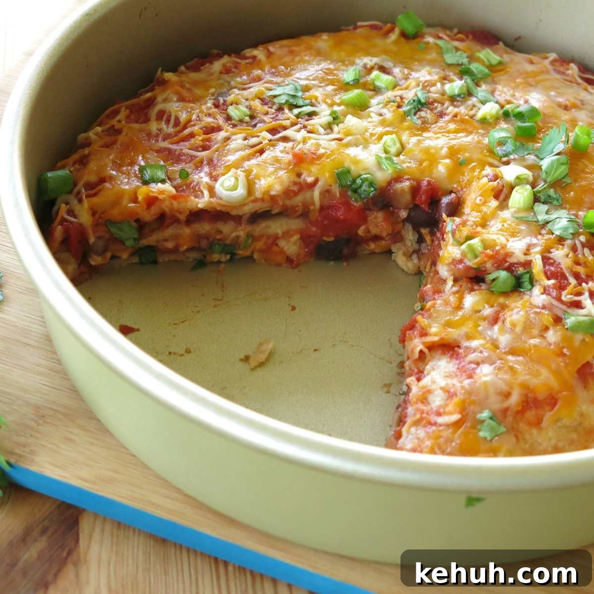 Stacked Burrito Pie: Cheesy Mexican Casserole Recipe 2 Layered burrito pie casserole in a round tin with a slice missing, exposing the layers.