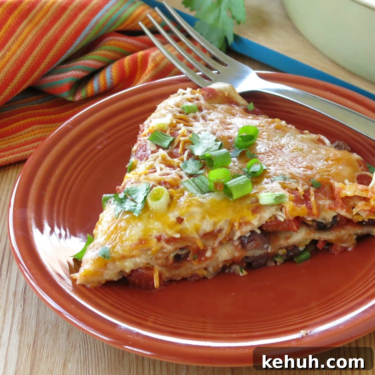 Stacked Burrito Pie: Cheesy Mexican Casserole Recipe 4 Slice of layered burrito pie casserole on plate with a fork