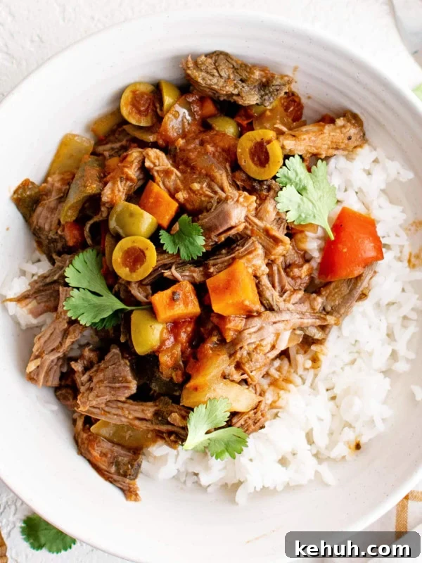 Authentic Cuban Ropa Vieja Recipe — Slow-Cooked Shredded Beef 14 Slow cooker picadillo pot roast with tender beef, olives, tomatoes, and bell peppers served over white rice and garnished with fresh cilantro.