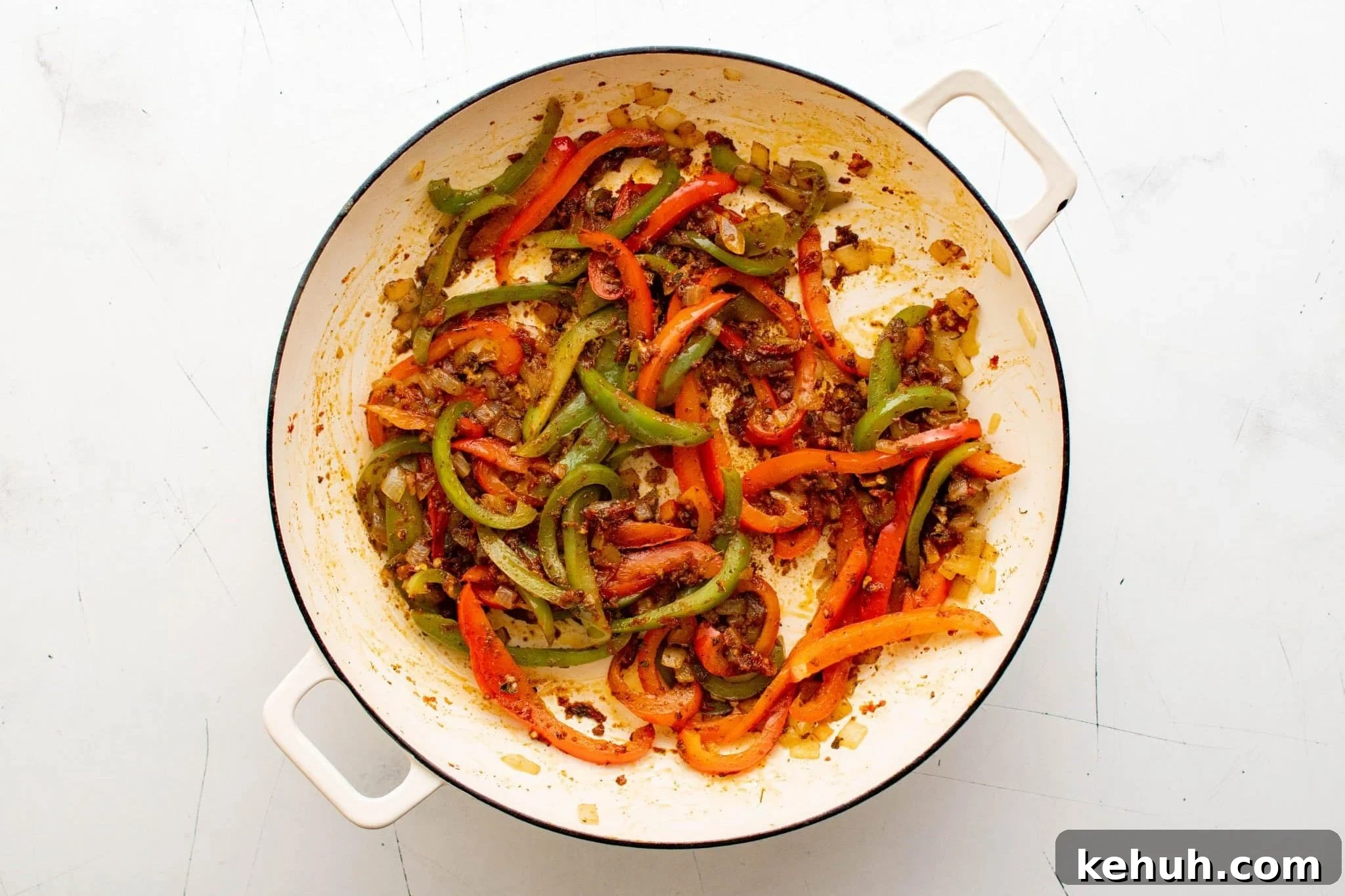 Authentic Cuban Ropa Vieja Recipe — Slow-Cooked Shredded Beef 8 Cooked peppers and onions coated with tomato paste and spices in a skillet.