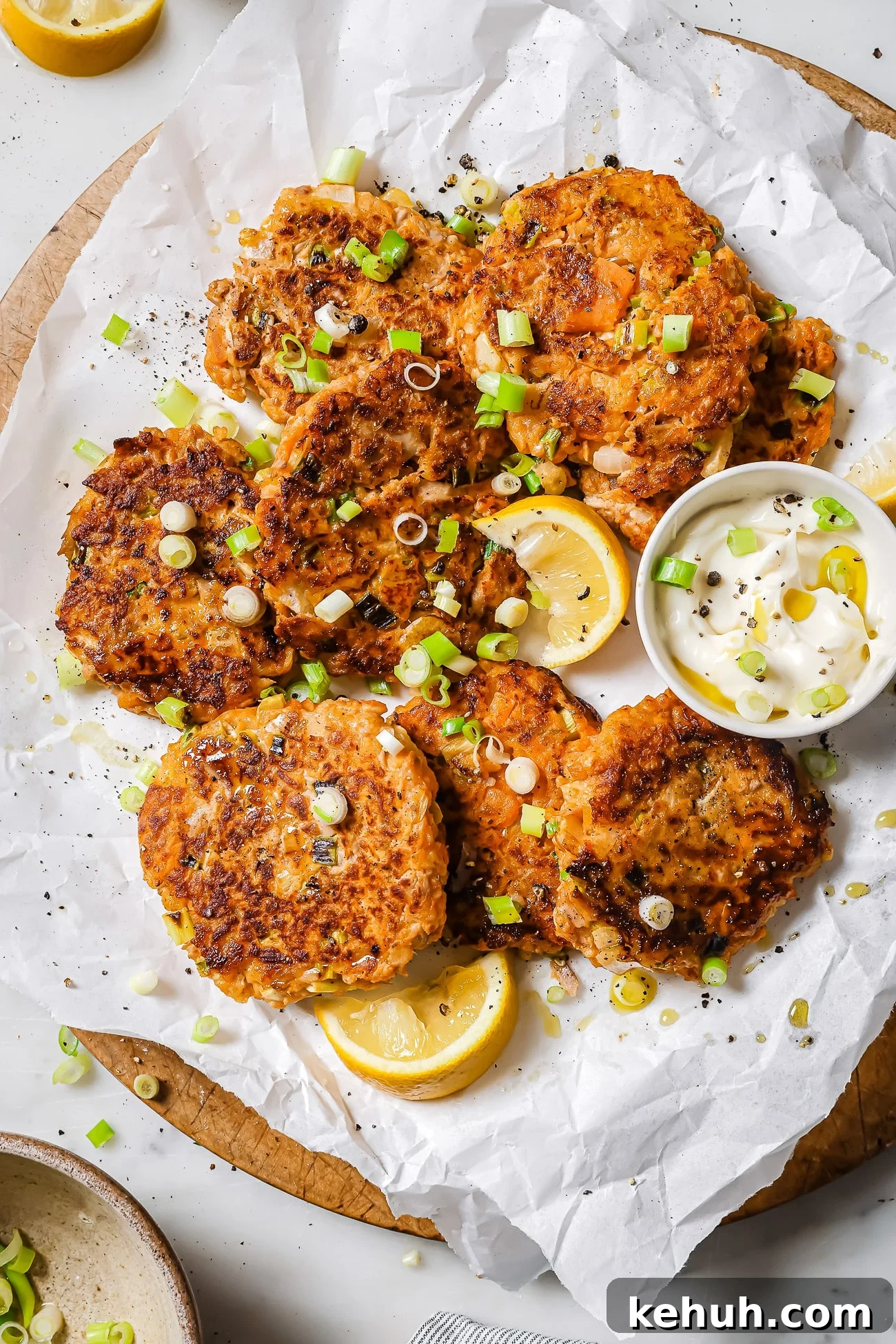 Tuna patties with sweet potato on parchment paper garnished with scallions.