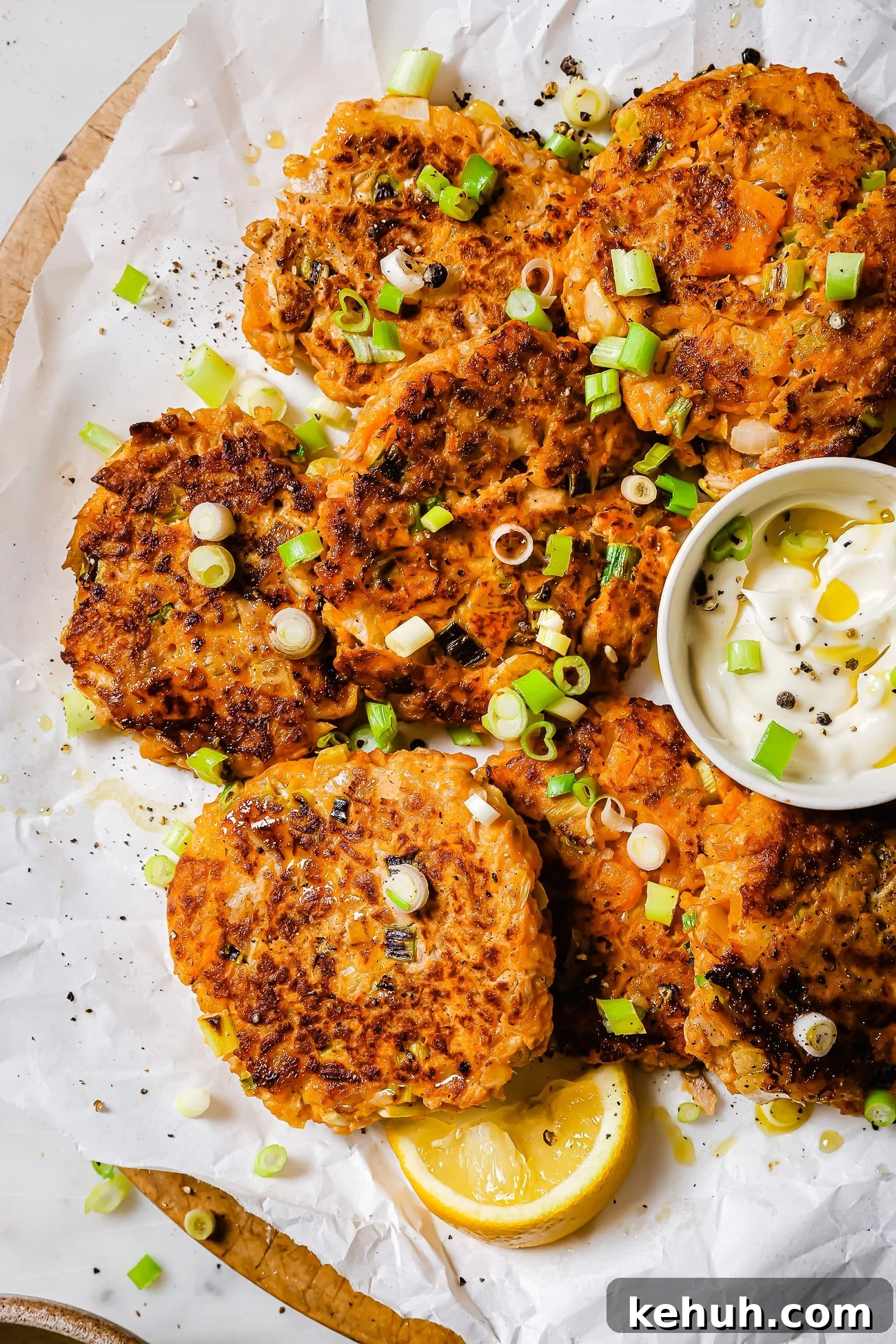 Tuna patties with sweet potato on parchment paper garnished with scallions.