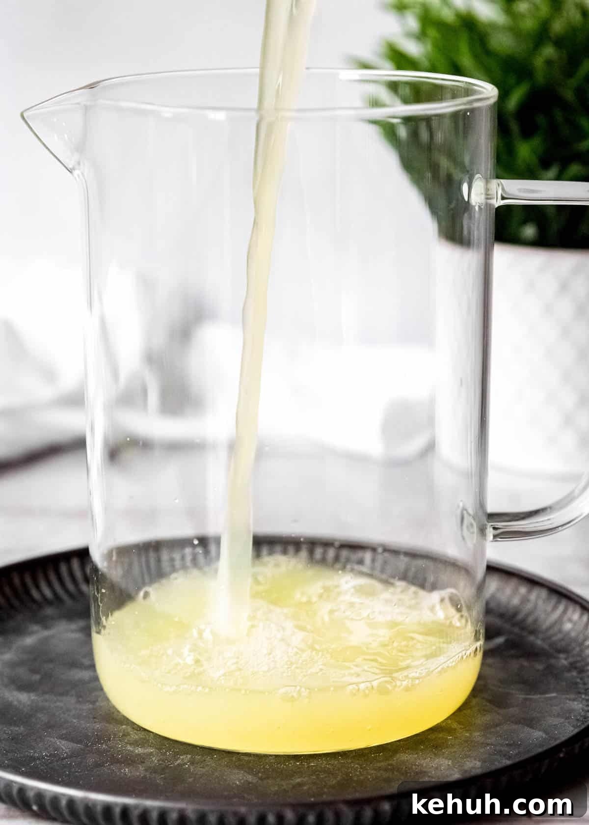 Peach Bourbon Lemonade Recipe — Refreshing Summer Cocktail 5 fresh lemon juice being poured into a pitcher