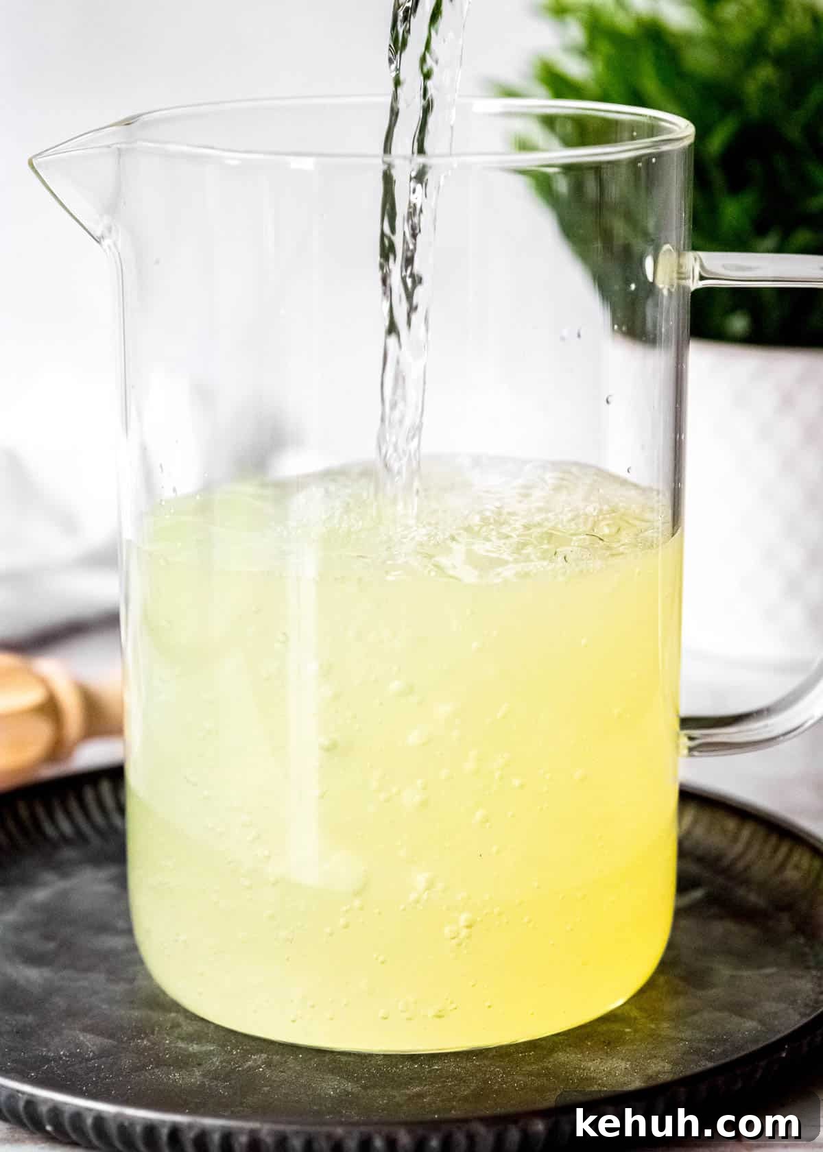 Peach Bourbon Lemonade Recipe — Refreshing Summer Cocktail 6 water pouring into a pitcher with lemon juice