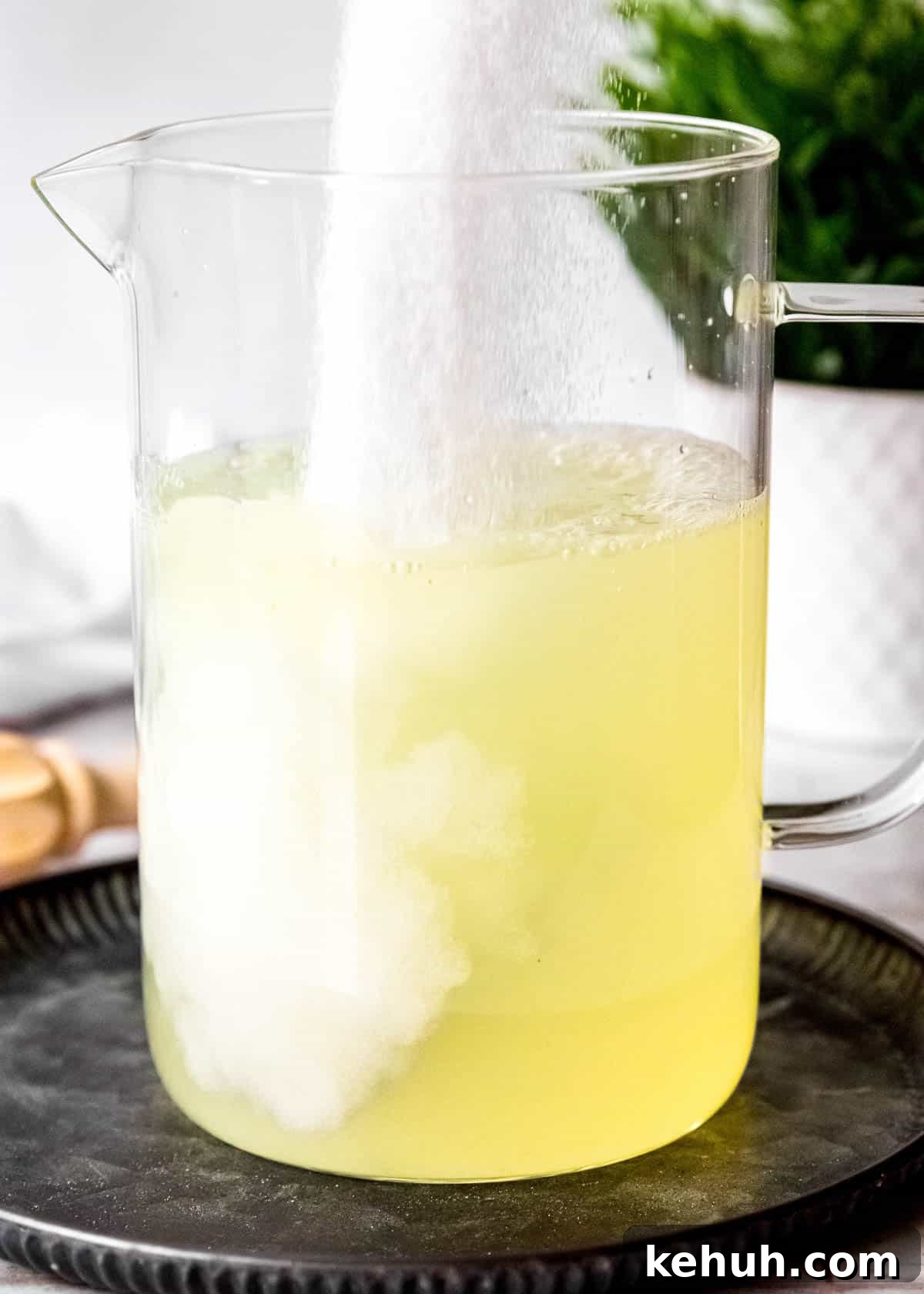 Peach Bourbon Lemonade Recipe — Refreshing Summer Cocktail 7 sugar pouring into a pitcher with lemon juice and water