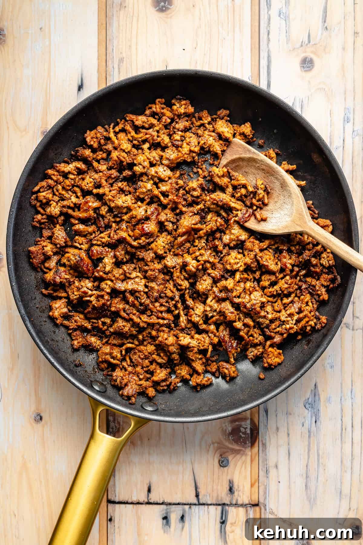 Street Corn & Sweet Potato Beef Bowl Recipe — Flavor-Packed Meal 6 A skillet filled with cooked, seasoned ground meat and a wooden spoon resting on the side, placed on a light wooden surface.