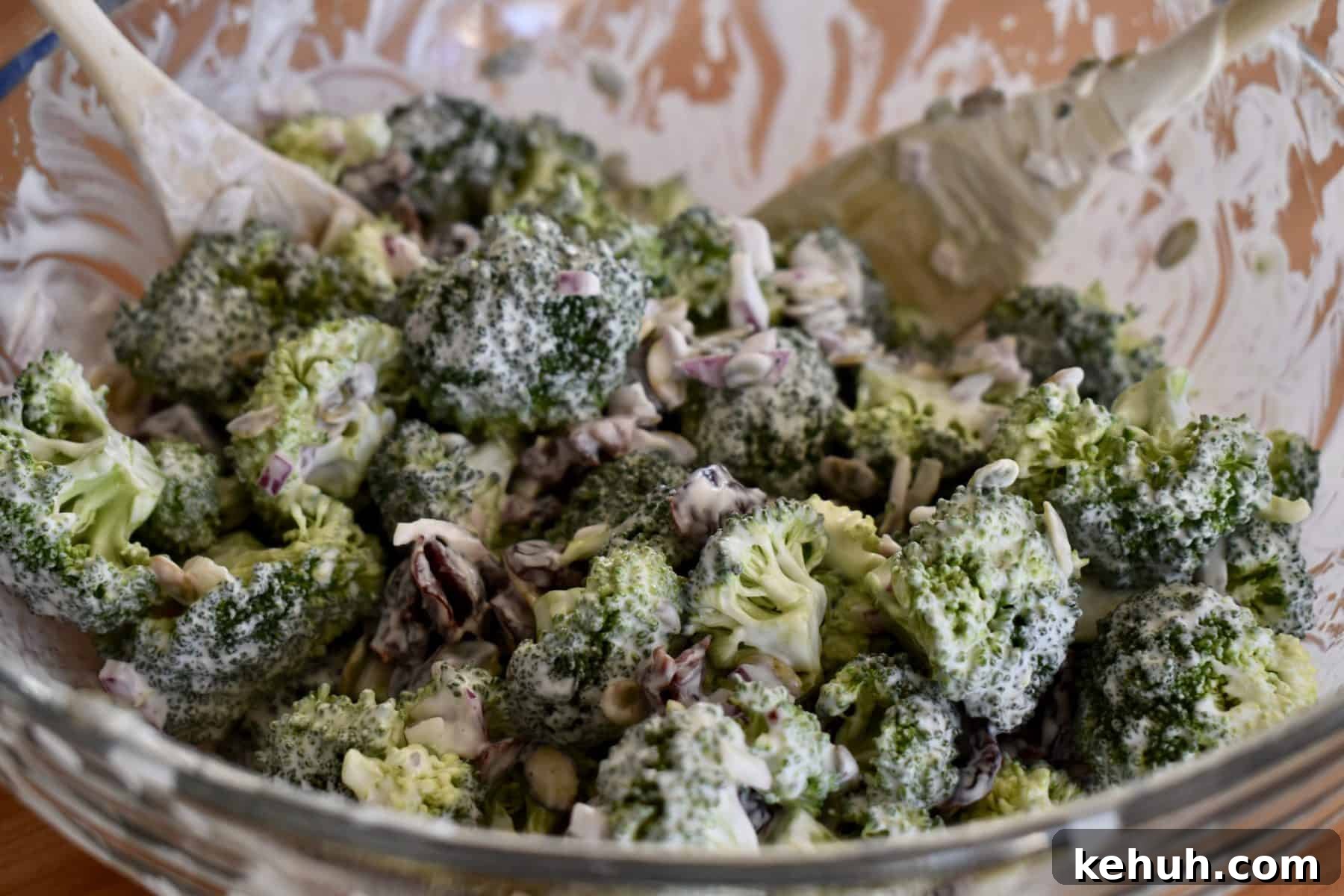 tossed broccoli cranberry salad with greek yogurt dressing in a glass bowl. 