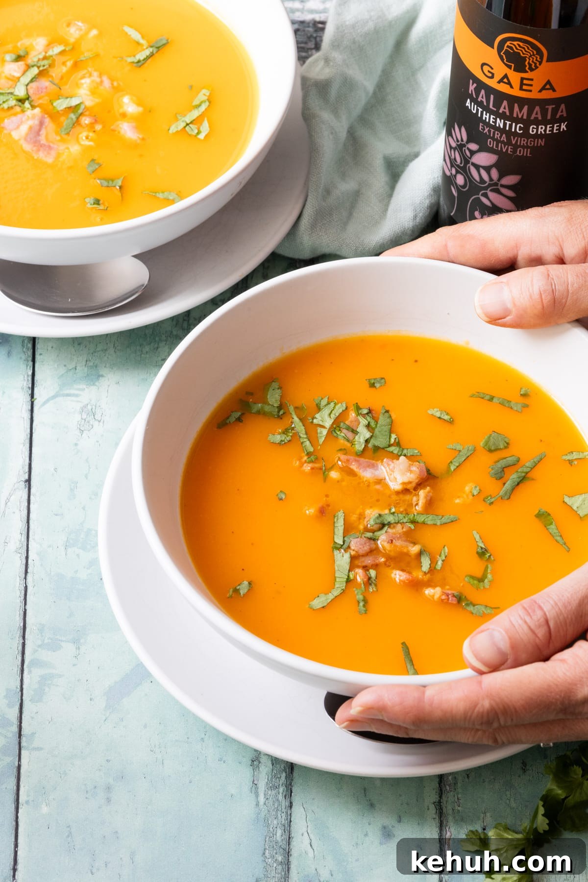 hands holding a bowl of butternut squash soup